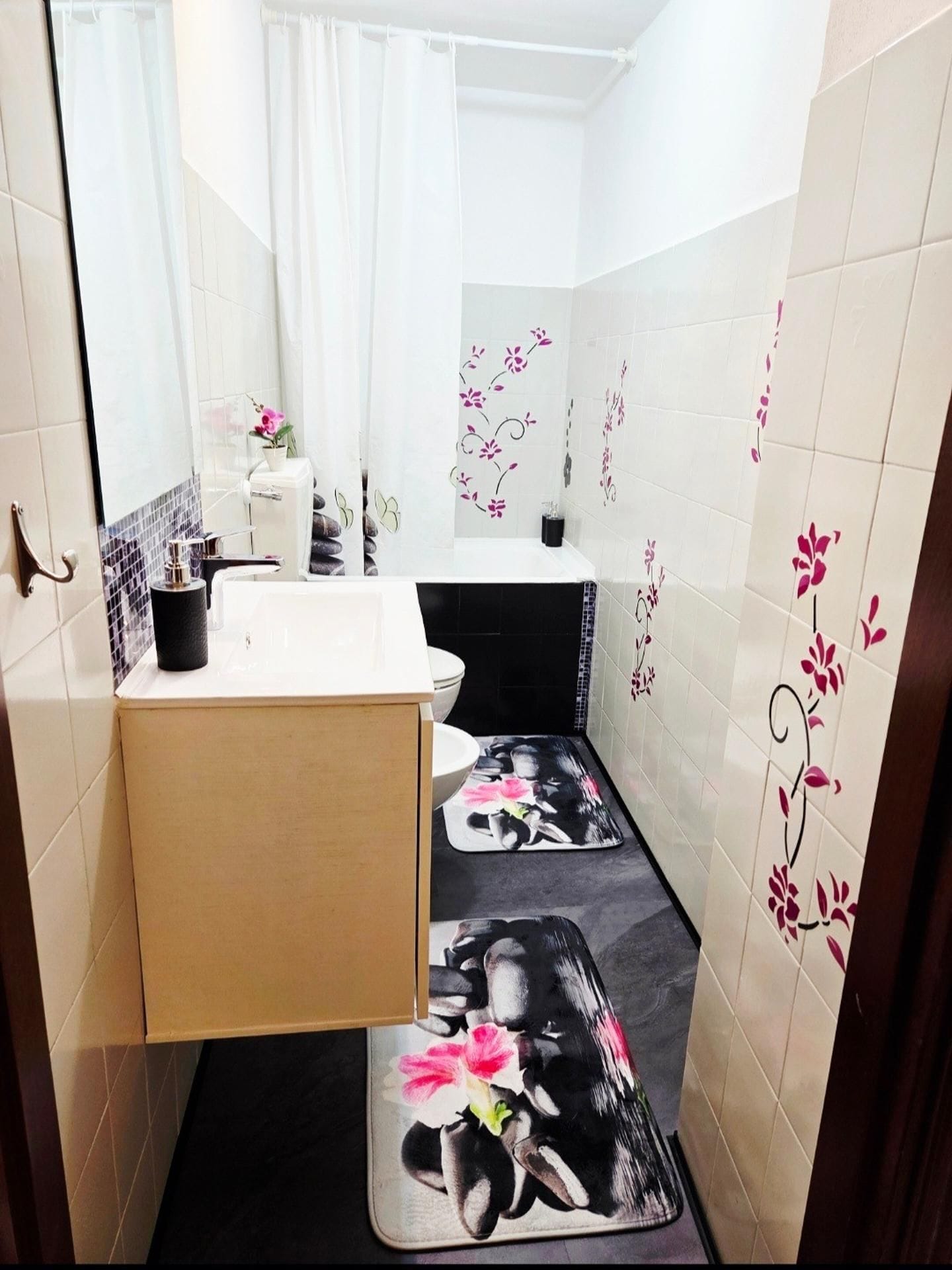 Une petite salle de bain avec un lavabo blanc, un miroir, des toilettes et un espace douche.