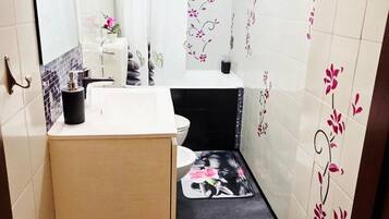 Une petite salle de bain avec un lavabo blanc, un miroir, des toilettes et un espace douche.