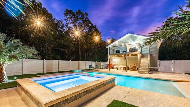 A backyard with a swimming pool, a hot tub, and a covered patio area.