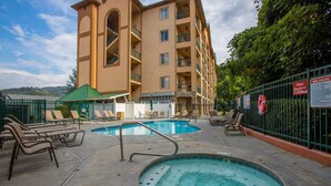 A hotel pool area with two pools, lounge chairs, and a hot tub.