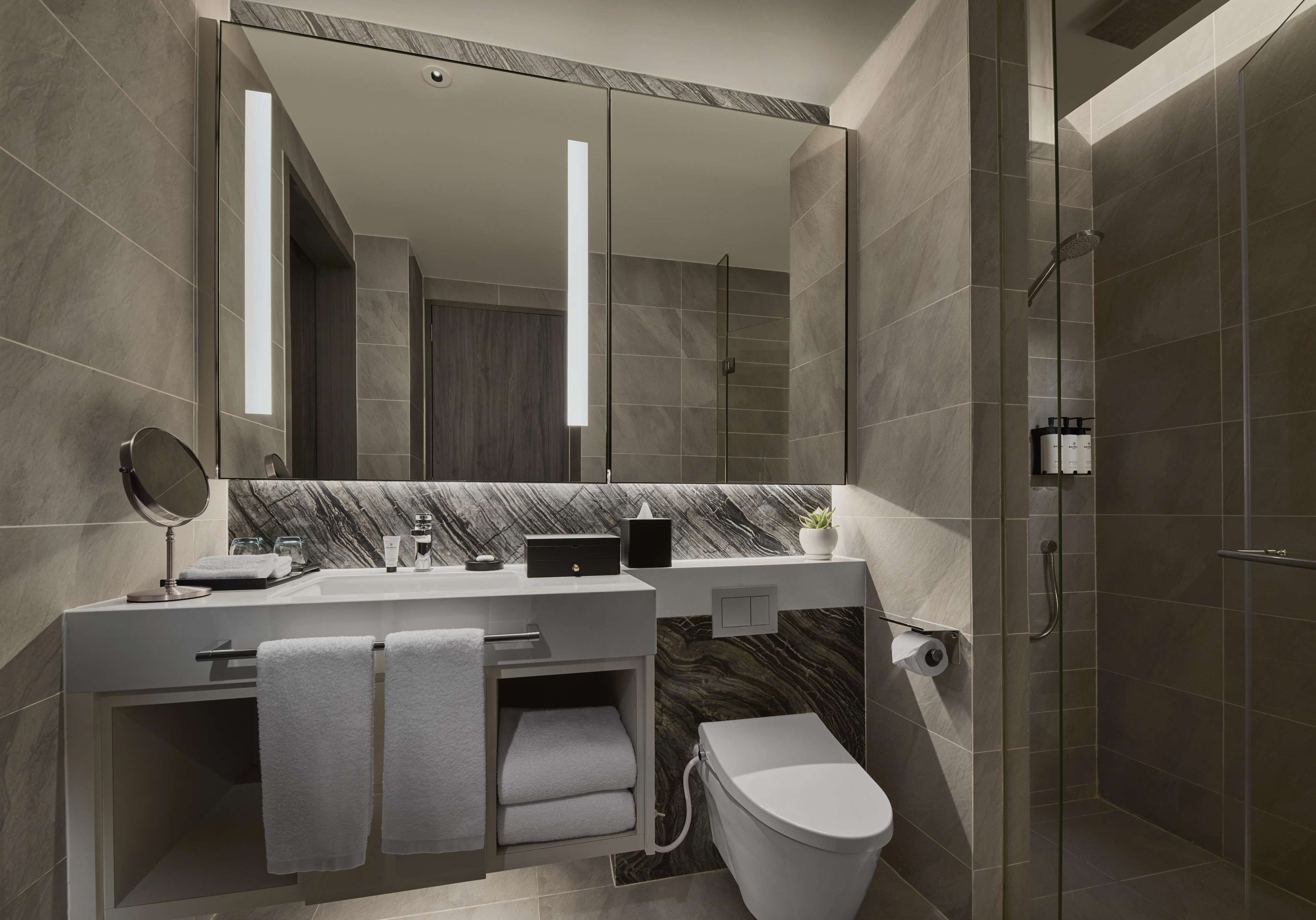A modern bathroom with a large mirror, a toilet, and a shower area.