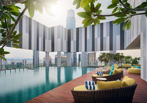 Una piscina infinita en la azotea con muebles de mimbre modernos y vistas a la ciudad.