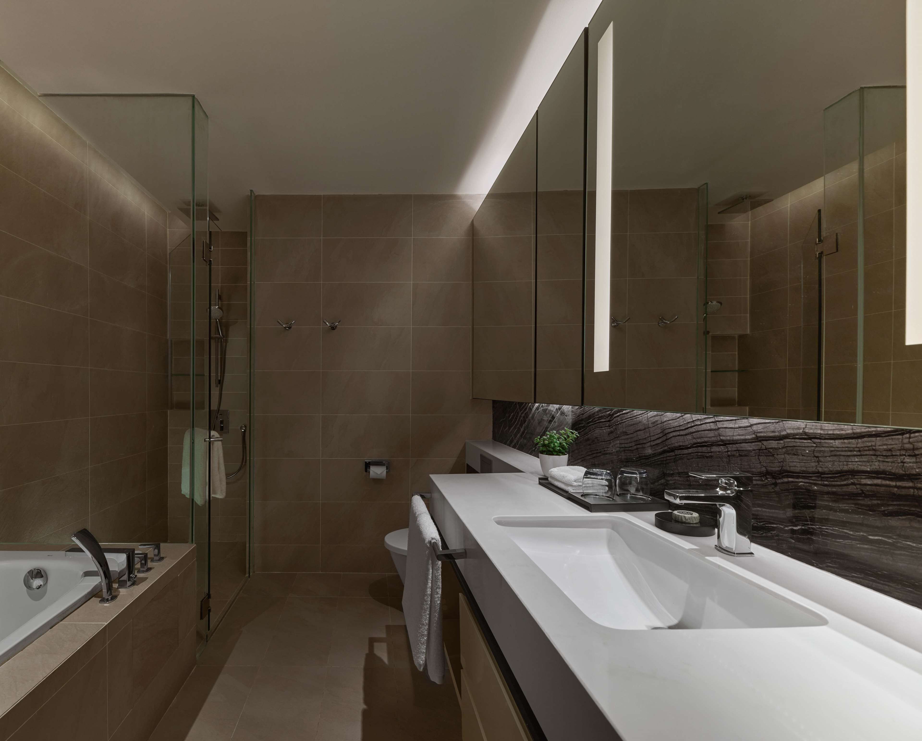 A modern bathroom with a glass shower enclosure, a double sink vanity, and a large mirror.