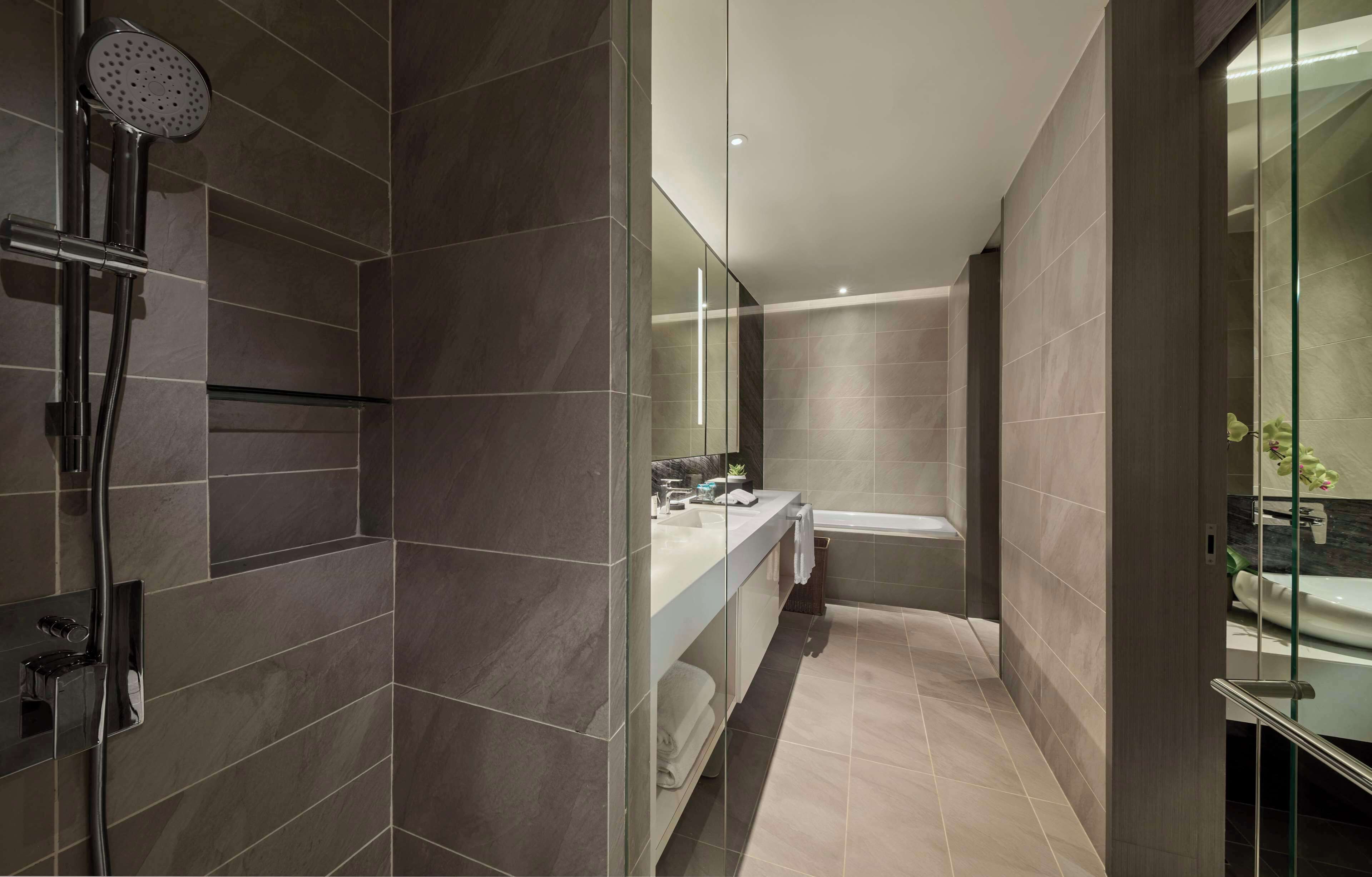 A modern bathroom with a glass shower enclosure, a vanity with a mirror, and a bathtub.