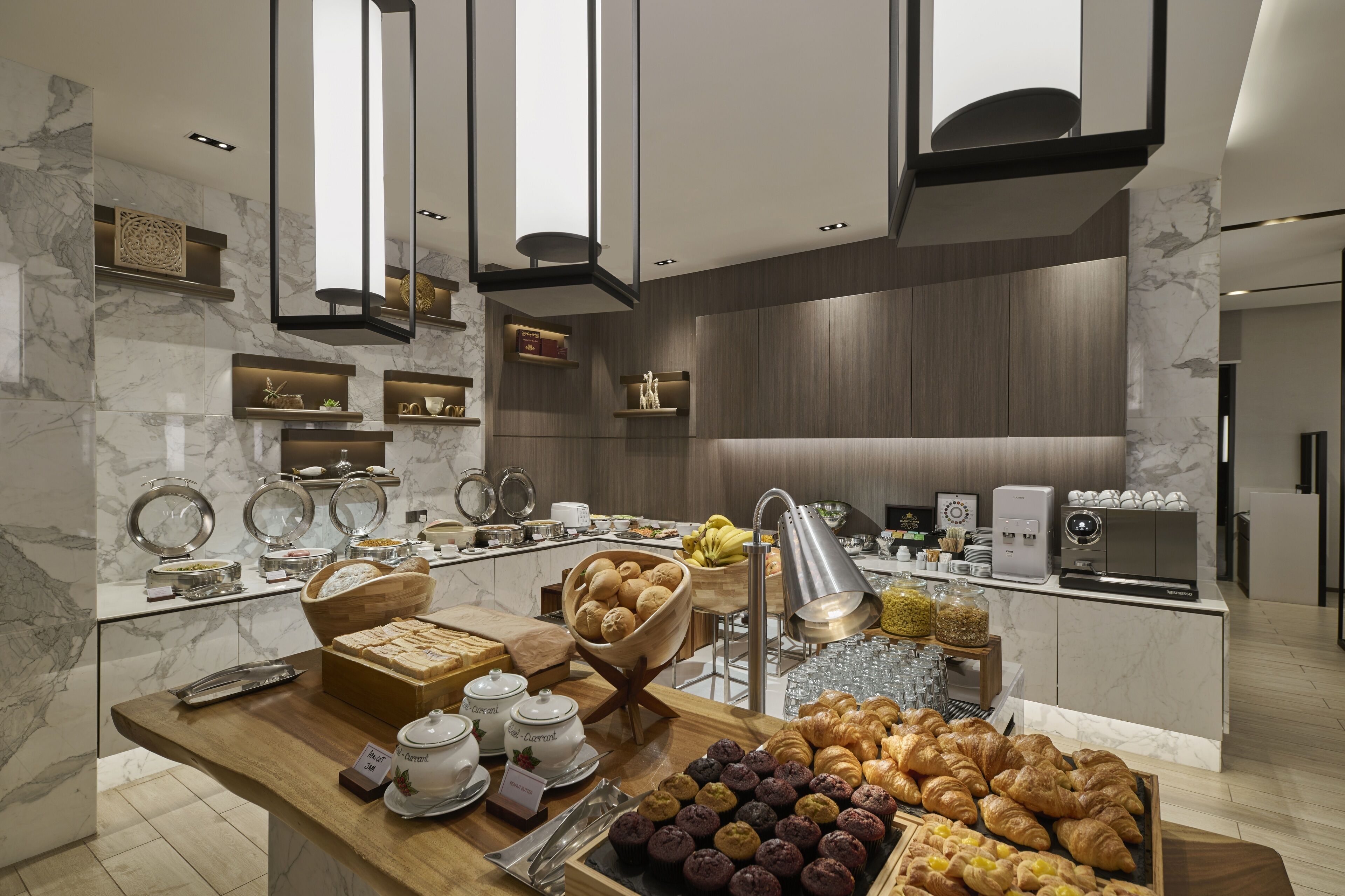 A modern breakfast buffet with marble countertops, a variety of pastries, and a coffee station.