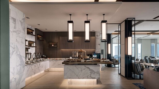 Een moderne keuken met marmeren aanrechtbladen, hanglampen en een centraal kookeiland met etenswaren.