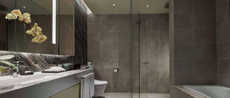 Un baño moderno con ducha envuelta en vidrio, bañera y tocador de mármol.