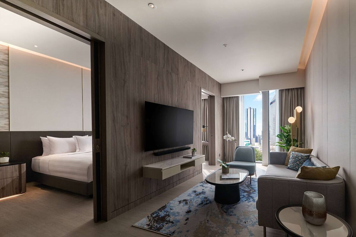Une chambre d’hôtel moderne équipée d’un lit, d’un téléviseur à écran plat, d’un canapé, d’une table basse et offrant une vue sur la ville.