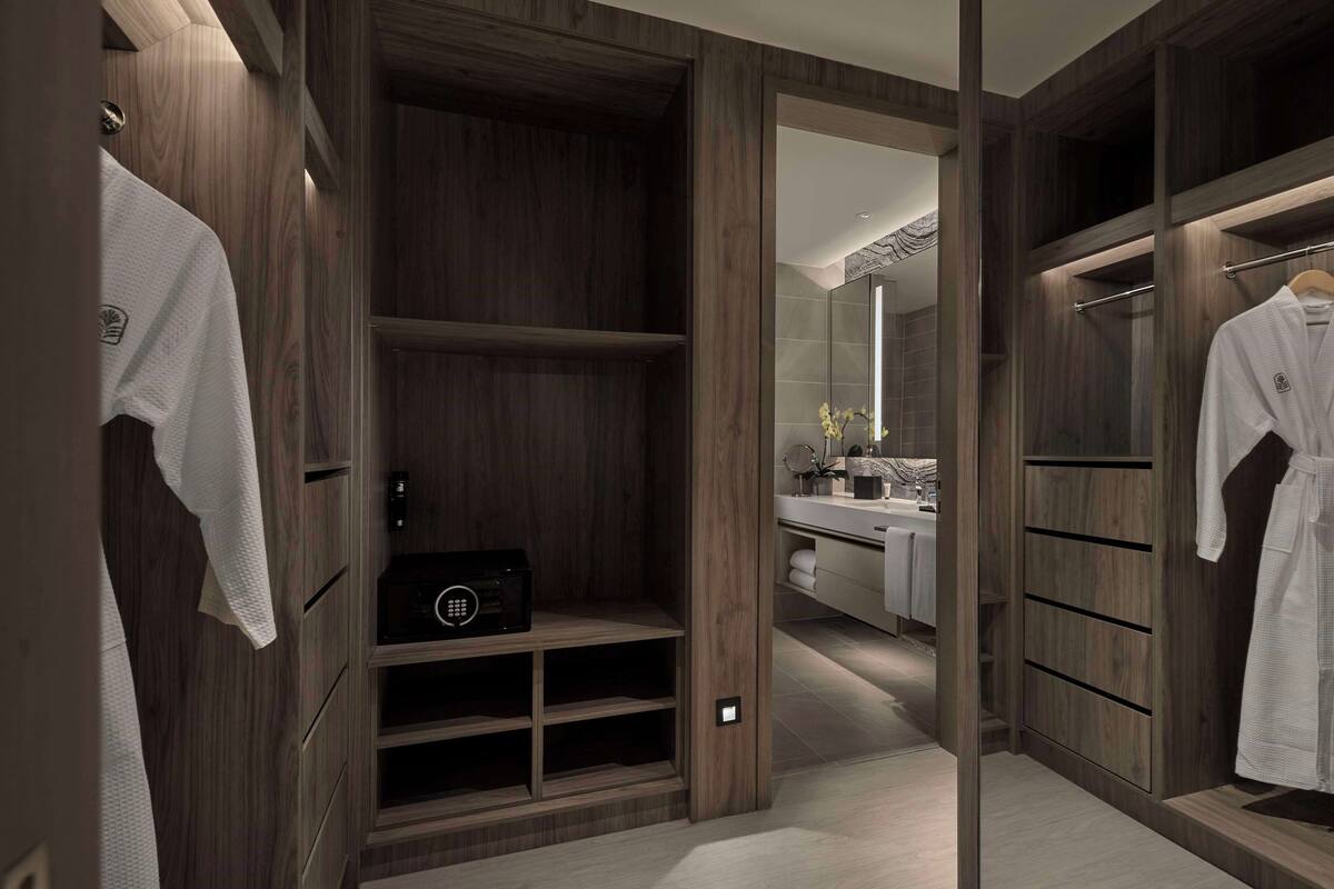 Un dressing avec des étagères en bois, une coiffeuse avec un miroir et un peignoir suspendu sur le côté droit.