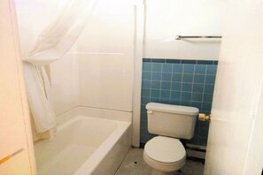 A small bathroom with a bathtub, toilet, and blue-tiled walls. - Love Hotels Desert Inn & RV at Boysen Wind River (Shoshoni)