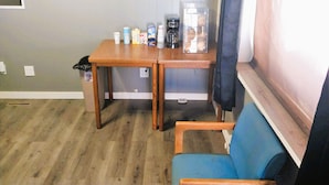 A small room with a wooden table, a blue chair, and a window with a curtain. - Love Hotels Desert Inn & RV at Boysen Wind River (Shoshoni)
