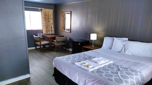 A hotel room with a bed, a desk, a chair, a lamp, and a window with curtains. - Love Hotels Desert Inn & RV at Boysen Wind River (Shoshoni)
