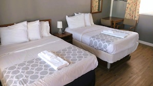 Two double beds with matching headboards and footboards, a bedside table with a lamp, and a wooden floor. - Love Hotels Desert Inn & RV at Boysen Wind River (Shoshoni)