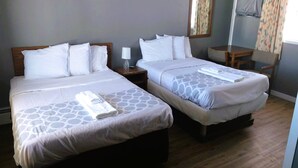 A hotel room with two beds, each with a pillow and a bedside table with a lamp. - Love Hotels Desert Inn & RV at Boysen Wind River (Shoshoni)