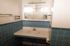 A bathroom with a sink, mirror, and blue-tiled walls. - Love Hotels Desert Inn & RV at Boysen Wind River (Shoshoni)