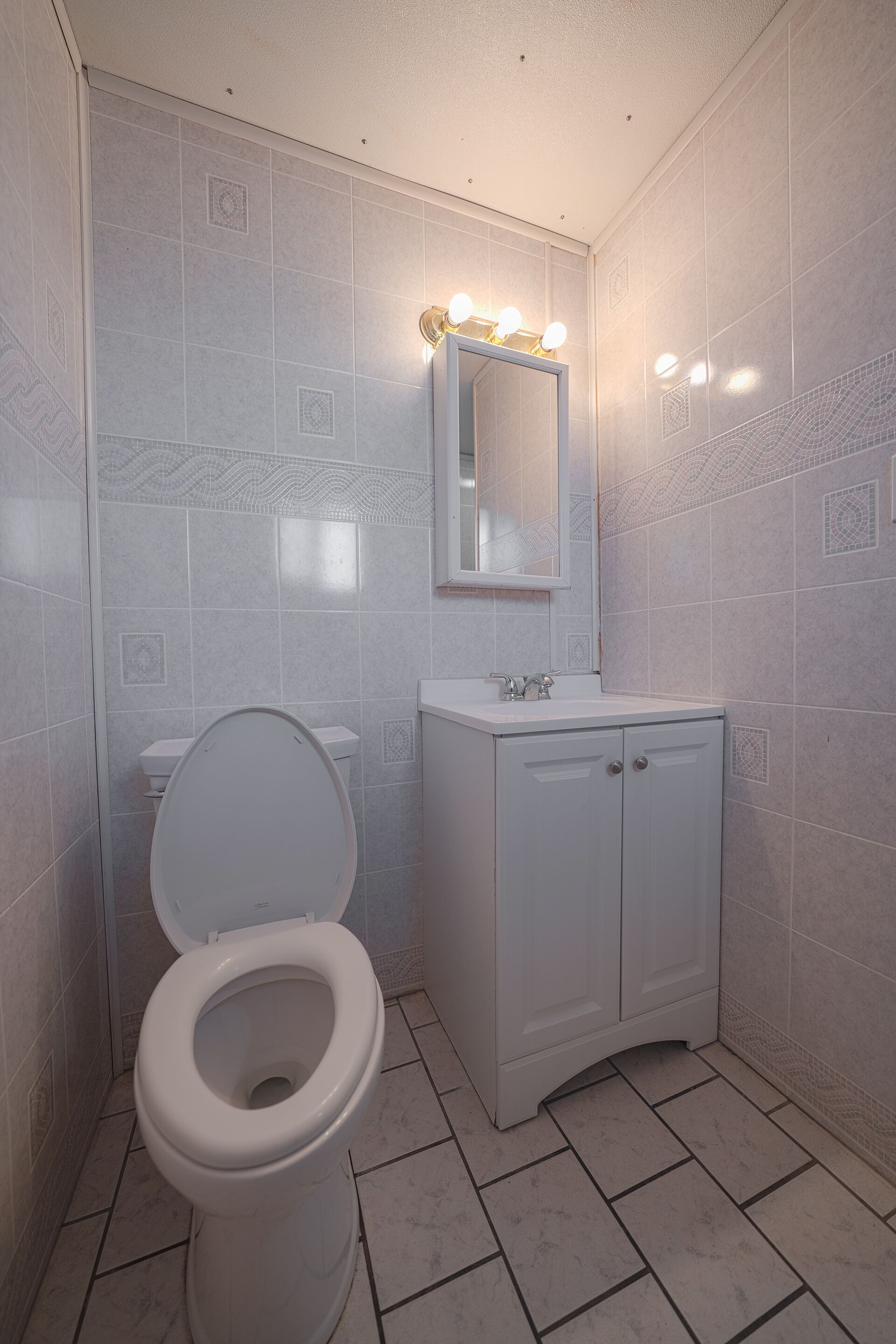 A bathroom with a toilet, sink, and mirror.