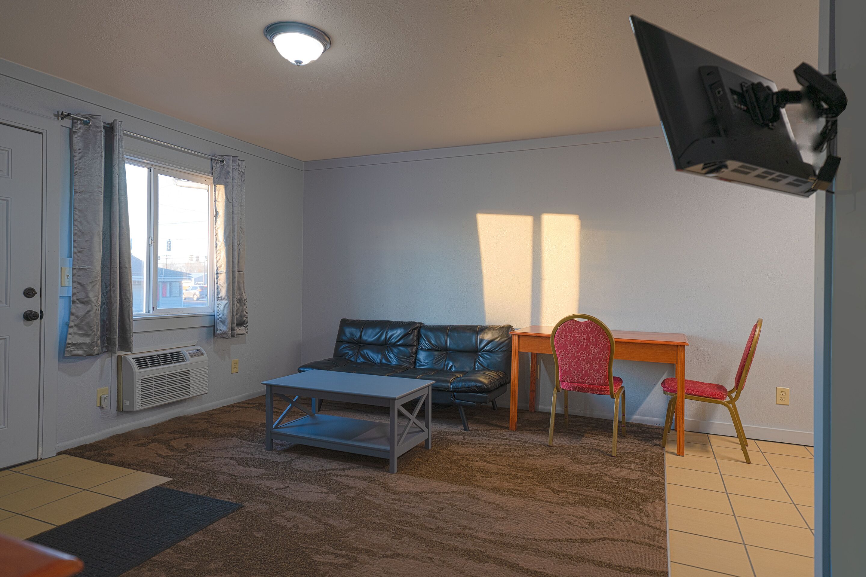 Een woonkamer met een bank, een salontafel en een aan de muur bevestigde televisie.