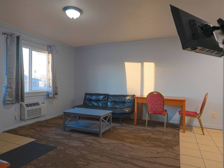 Een woonkamer met een bank, een salontafel en een aan de muur bevestigde televisie.