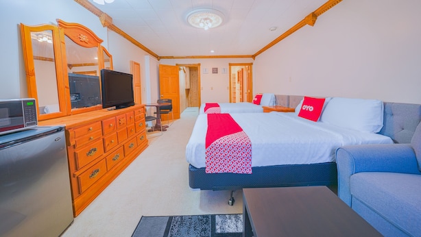 A hotel room with a bed, a sofa, a TV, a dresser, and a microwave. - Oyo Hotel Portland Or Near Airport (Portland)