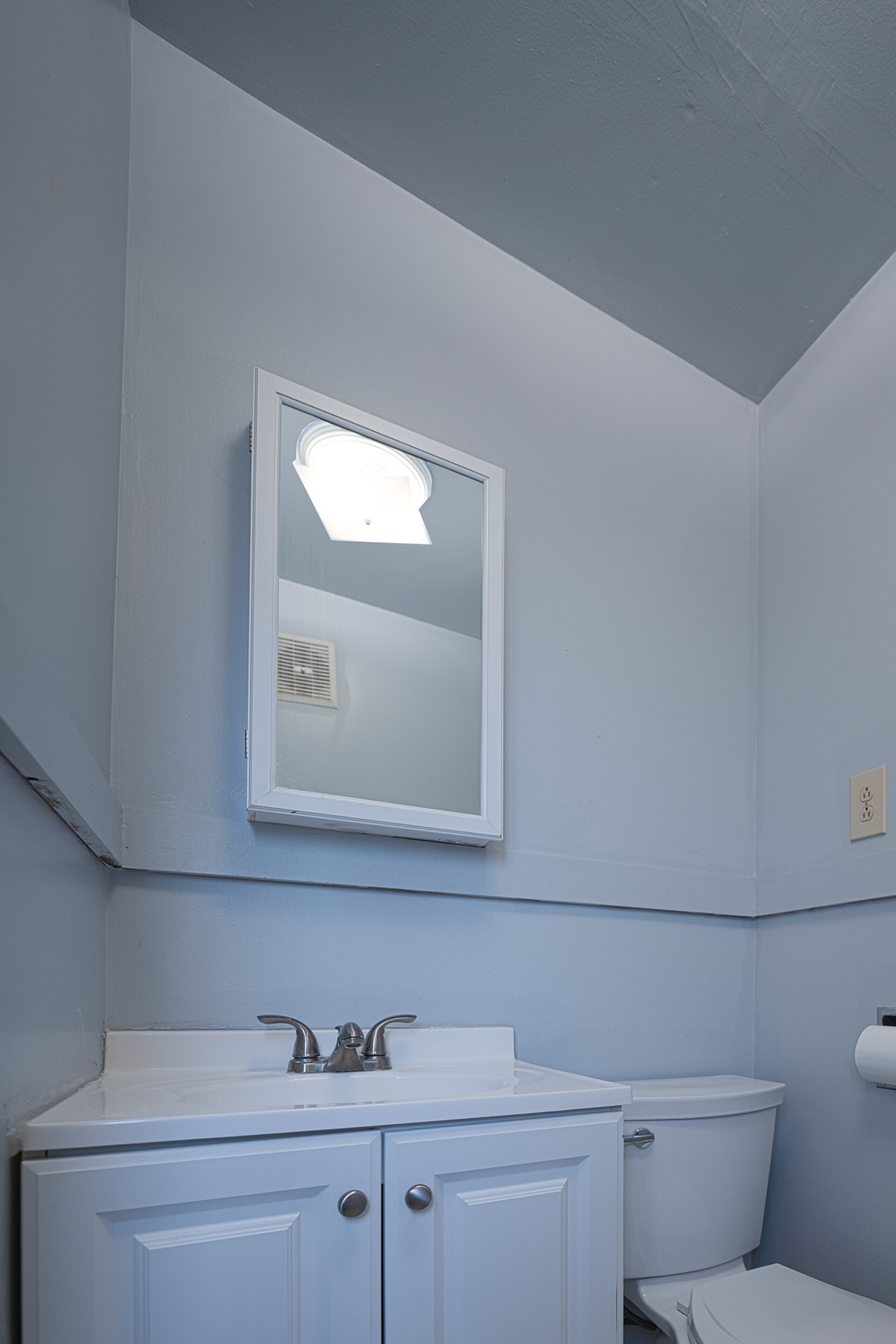 Un bagno con lavandino, specchio e water bianchi.