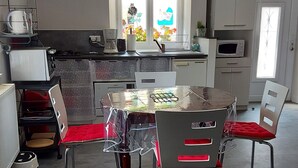 Moderni keittiö, jossa on ruokapöytä, tuoleja ja ikkuna, jonka ääressä on taideteos.