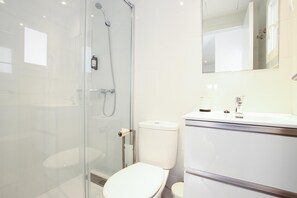 A modern bathroom with a glass shower enclosure, a white toilet, and a sink with a mirror above. - RIERES. Modern apartment near the beach. (Puerto Pollensa)