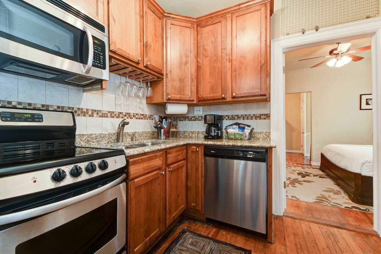 A compact kitchen with wooden cabinets, a microwave, a stove, and a dishwasher.