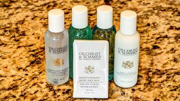 Quatre flacons de produits de soins pour la peau de la marque Gilchrist & Soames et un savon sur un comptoir en granit.
