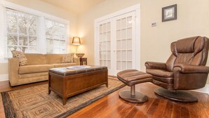 A living room with a brown leather chair, a beige sofa, and a wooden coffee table.