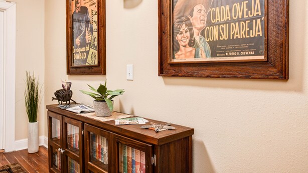 A hallway with a wooden console table displaying books and decorative items, flanked by two framed movie posters on the wall.
