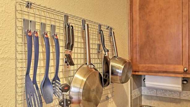 A kitchen with a wire rack holding various utensils and pots. - The Madison Riverwalk (San Antonio)