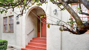 A building with a white exterior, red steps, and a red door.