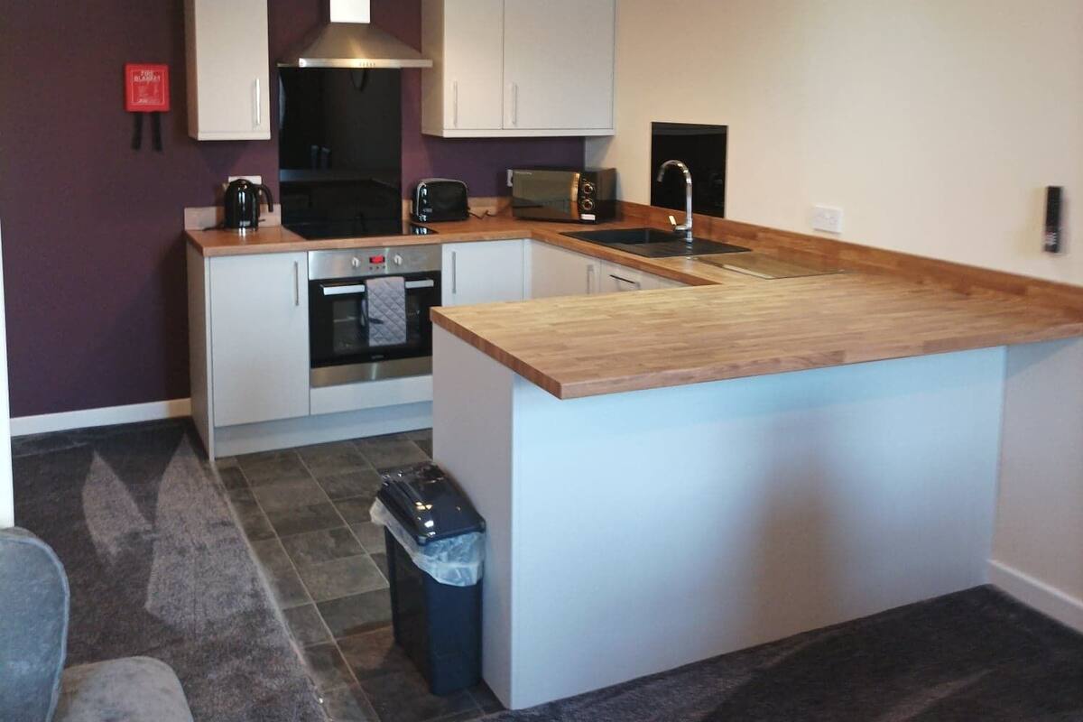 A modern kitchen with white cabinets, a wooden countertop, and a built-in oven.