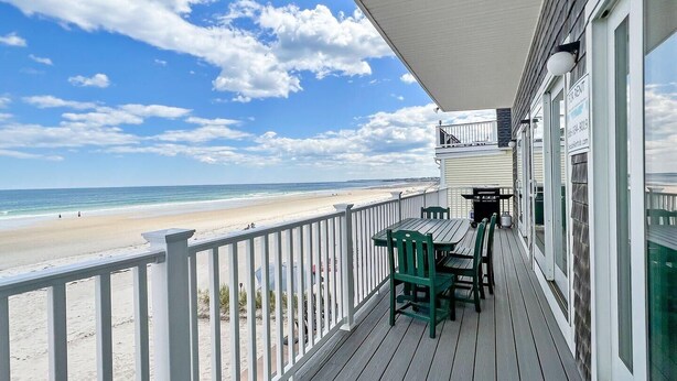 A wooden deck with a view of the beach, a table with chairs, and a sign indicating the property is for rent. - Sandcastle (Wells)