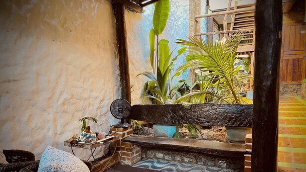 A cozy outdoor seating area with wicker furniture, a fan, and potted plants. - Pousada Açuncena (Itacaré)
