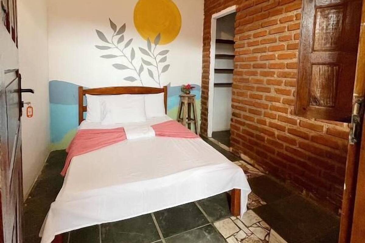 Ein Schlafzimmer mit Bett, Deckenventilator, Backsteinwand und Tür.