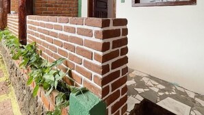 A brick wall with a window and a door, a ceiling fan, and a green painted post. - Pousada Açuncena (Itacaré)