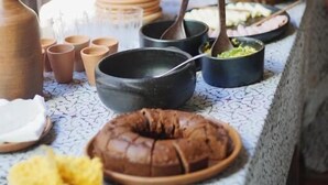 A table set with various dishes, including a bundt cake and bowls, in a rustic outdoor setting. - Pousada Açuncena (Itacaré)