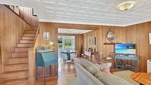 Een houten interieur met een trap, een bank, een televisie en een eethoek.