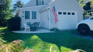 A two-story house with a garage, an American flag, a lawn, and a white car parked in the driveway. - Family Retreat at York Beach (York Beach)