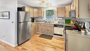 A modern kitchen with wooden cabinets, stainless steel appliances, and a window providing natural light. - Family Retreat at York Beach (York Beach)