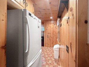 Eine kompakte Küche mit einem eingebauten Kühlschrank und einer kleinen Mülltonne.