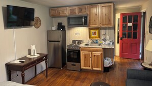 A compact kitchen with wooden cabinets, a stainless steel refrigerator, a microwave, and a gas stove.