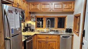 Una cucina con mobili in legno, un frigorifero in acciaio inossidabile, un forno a microonde, un lavello e una lavastoviglie.
