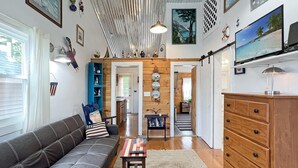 A cozy living room with a sofa, a coffee table, and a wooden dresser. There are framed pictures on the walls and a television on a stand. - Lighthouse - Q991 (Cape Neddick)