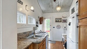 A kitchen with granite countertops, a sink, a stove, and a refrigerator. There are wooden cabinets and a window with a view of greenery outside. - Lighthouse - Q991 (Cape Neddick)