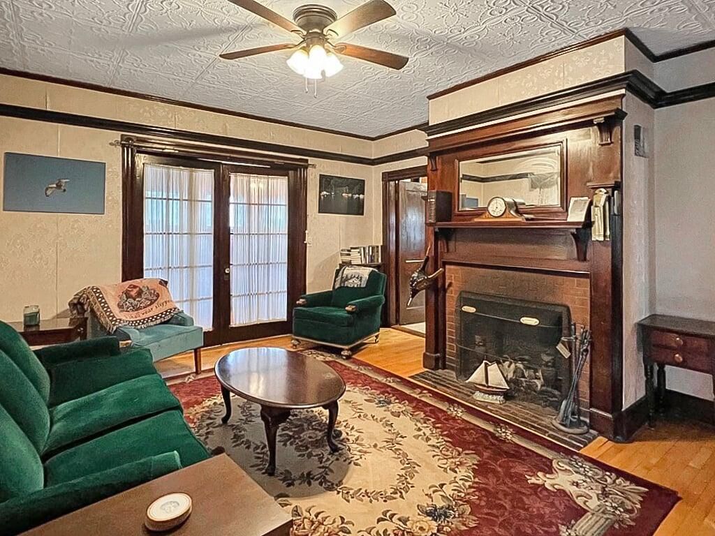 A living room with a fireplace, green armchairs, a coffee table, and a ceiling fan.