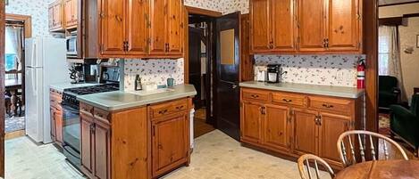 A kitchen with wooden cabinets, a stove, a refrigerator, and a dining table with chairs.