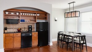 A modern kitchen with wooden cabinets, a black refrigerator, and a dining area with a table and chairs. - Getaway on the Riverwalk @ Riverside Suites- 1 Br Condo (San Antonio)