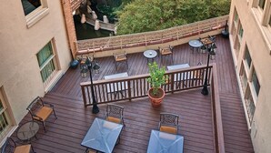 A wooden deck with outdoor seating, a potted plant, and a view of a water feature. - Getaway on the Riverwalk @ Riverside Suites- 1 Br Condo (San Antonio)